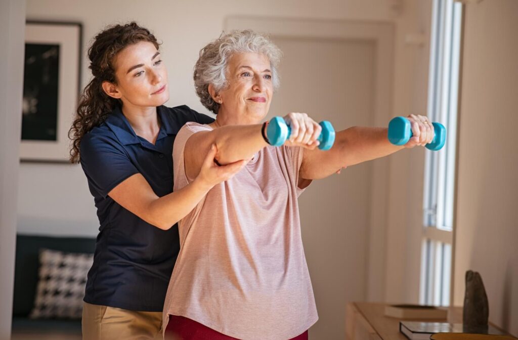 A caregiver assists a senior resident with strength exercises.
